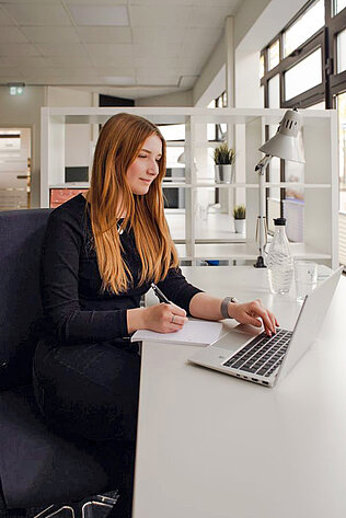 Eine Frau arbeitet an einem Laptop im Coworking Space.