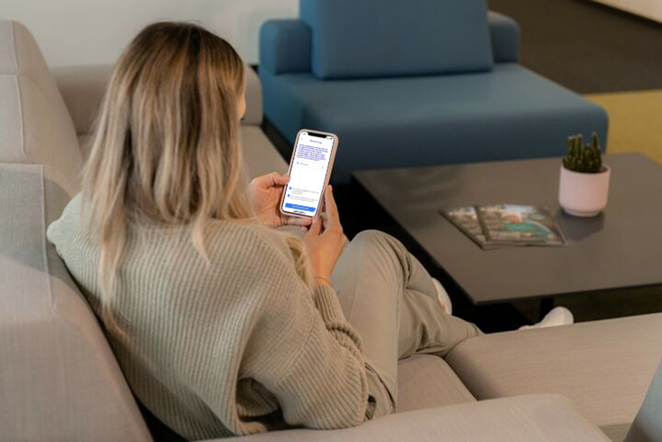 Eine Frau sitzt mit einem Smartphone in der Hand auf einer Couch Eine Frau sitzt mit einem Smartphone in der Hand auf einer Couch
