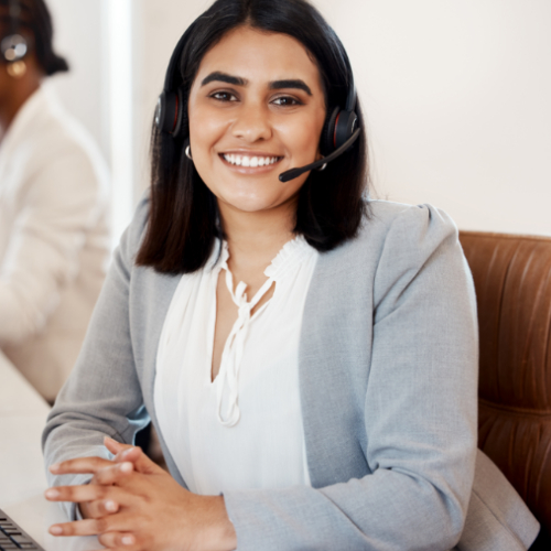 Eine Frau mit Headset sitzt lächelnd vor einer Tastatur.